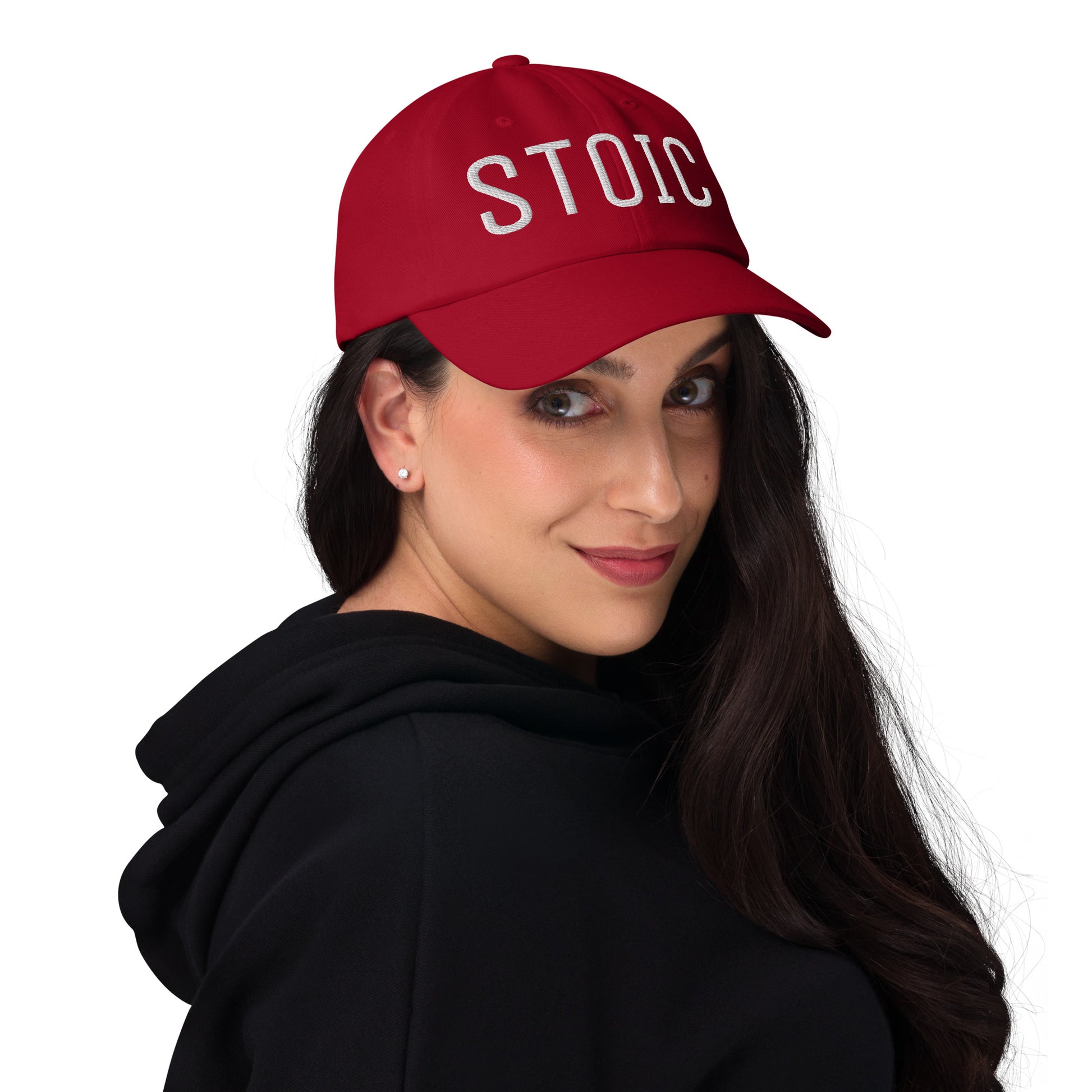 Red Stoic embroidered dad hat, front view, worn by model in black hoodie