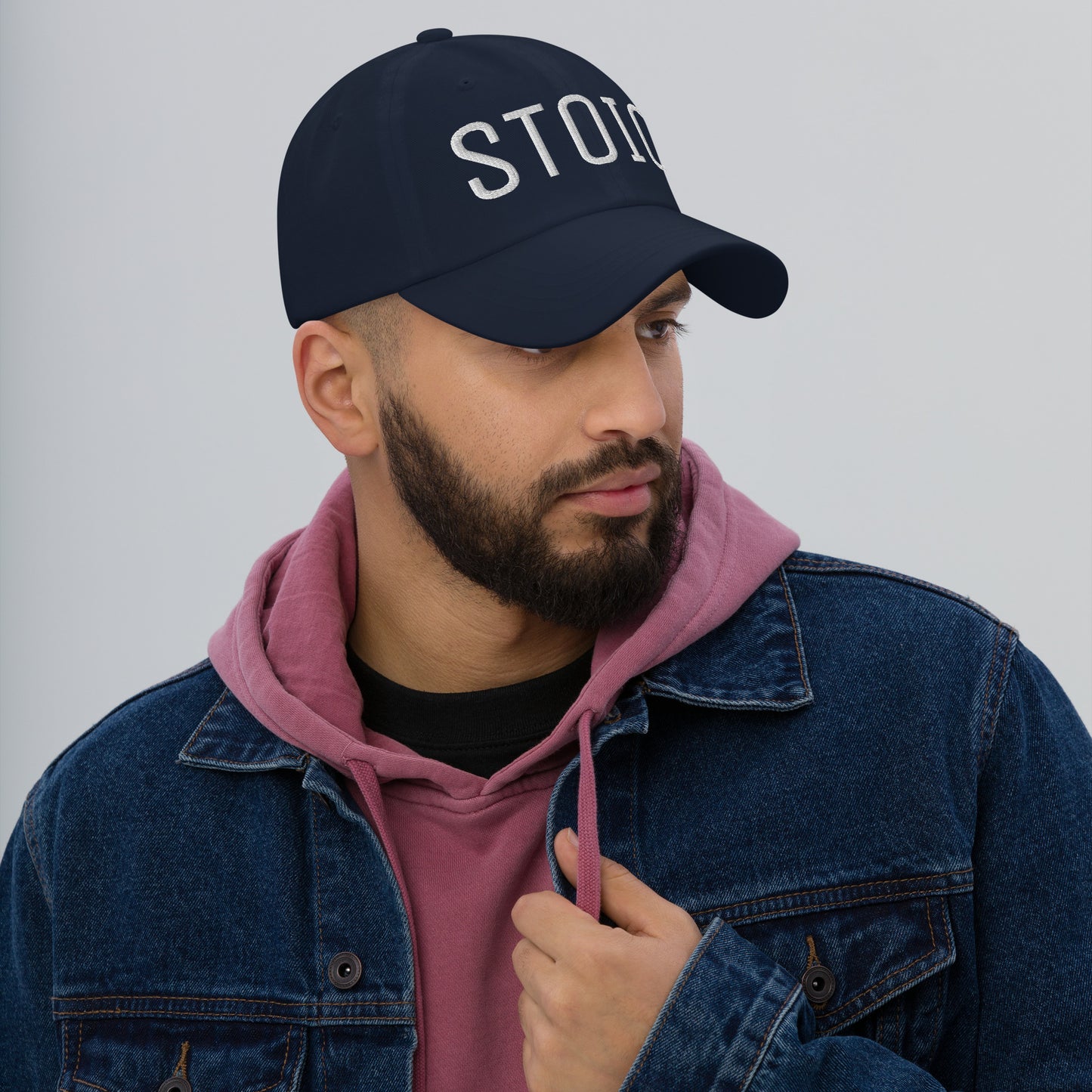 Man wearing navy Stoic embroidered dad hat styled with denim jacket and pink hoodie